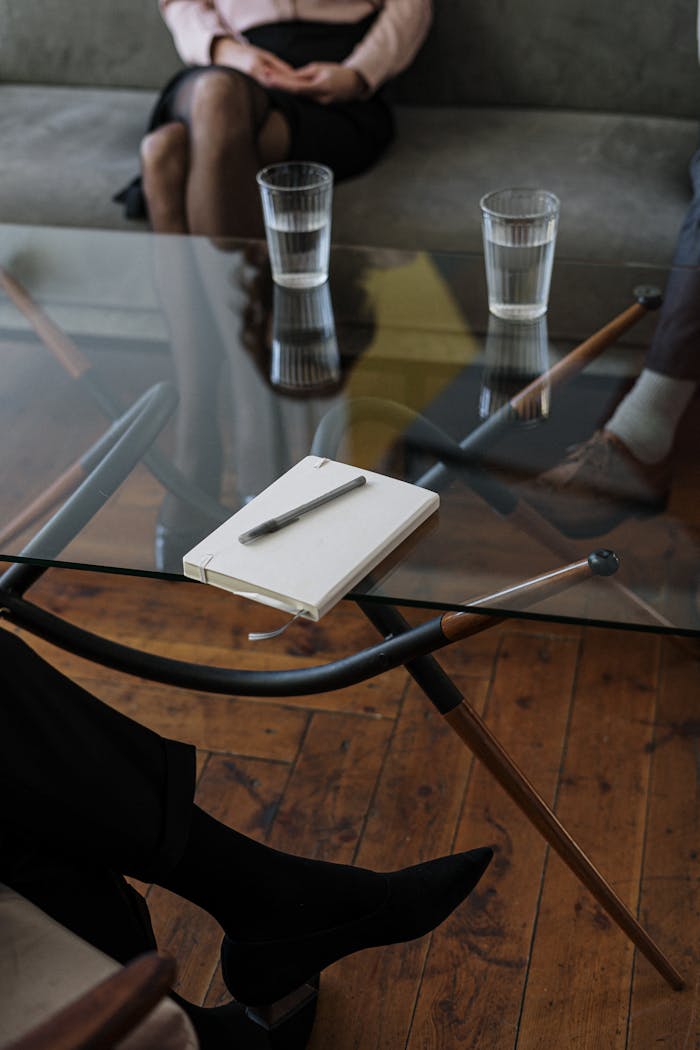 about-01 Close-up of a counseling session with two glasses of water and a notepad on a glass table.