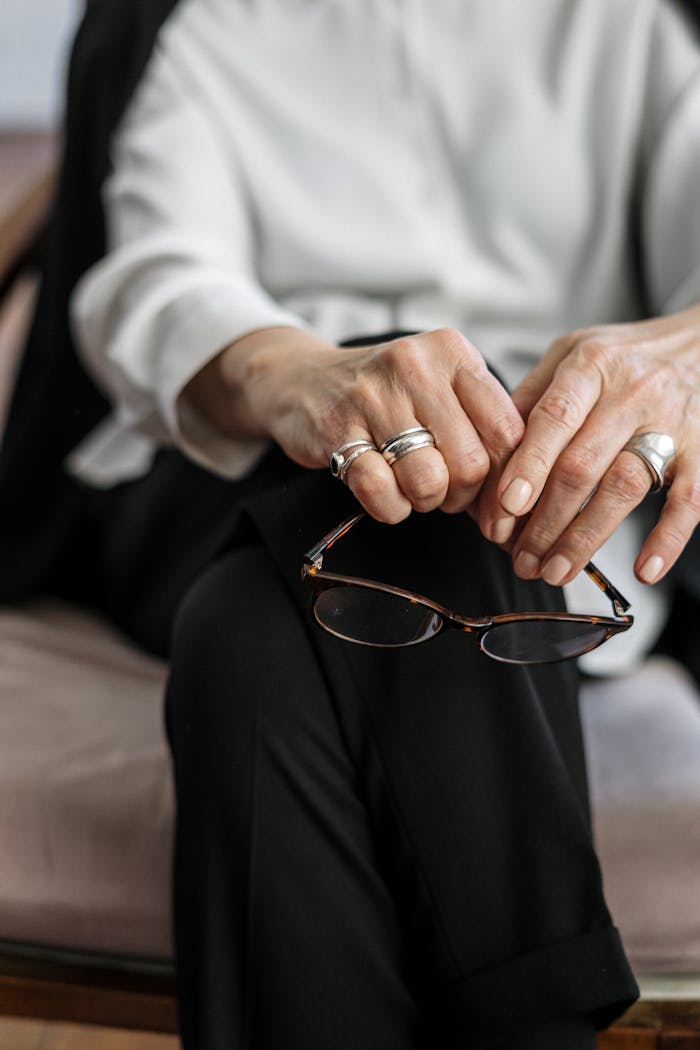 A close-up of a therapist's hands with glasses, symbolizing mental health support in a professional setting.