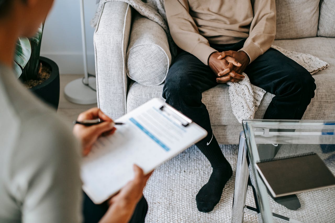 hero-img-01 Therapist takes notes as client sits on a sofa during a psychotherapy session.